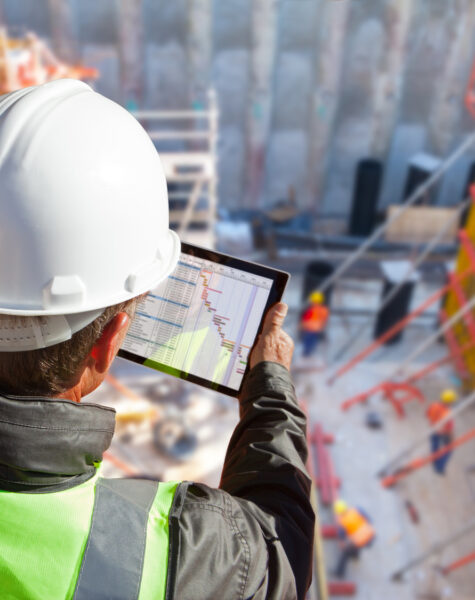 civil engineer or architect on construction site checking schedule with tablet computer