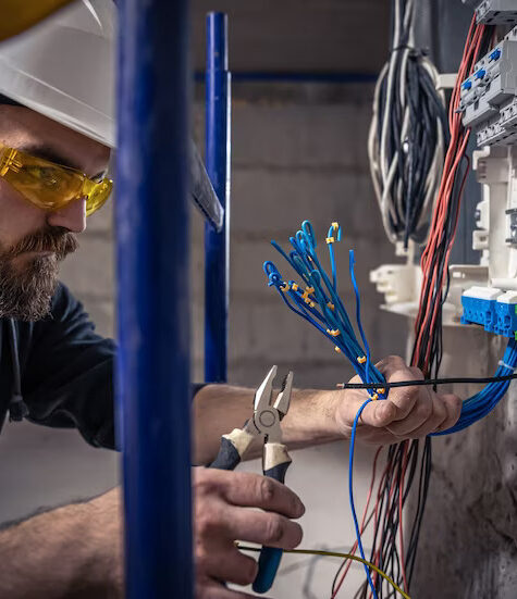 male-electrician-works-switchboard-with-electrical-connecting-cable_169016-15090